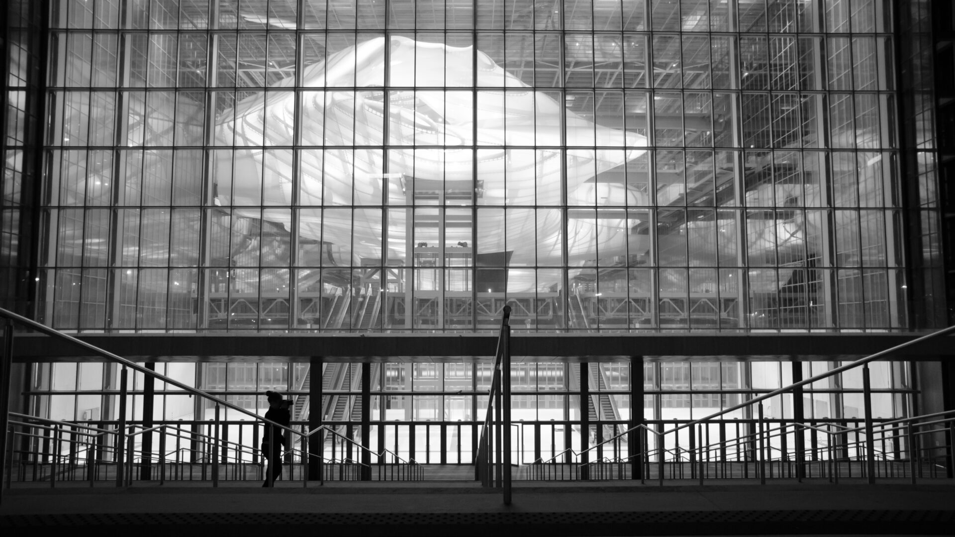 Human silhouette in front of modern glass facade in black and white.