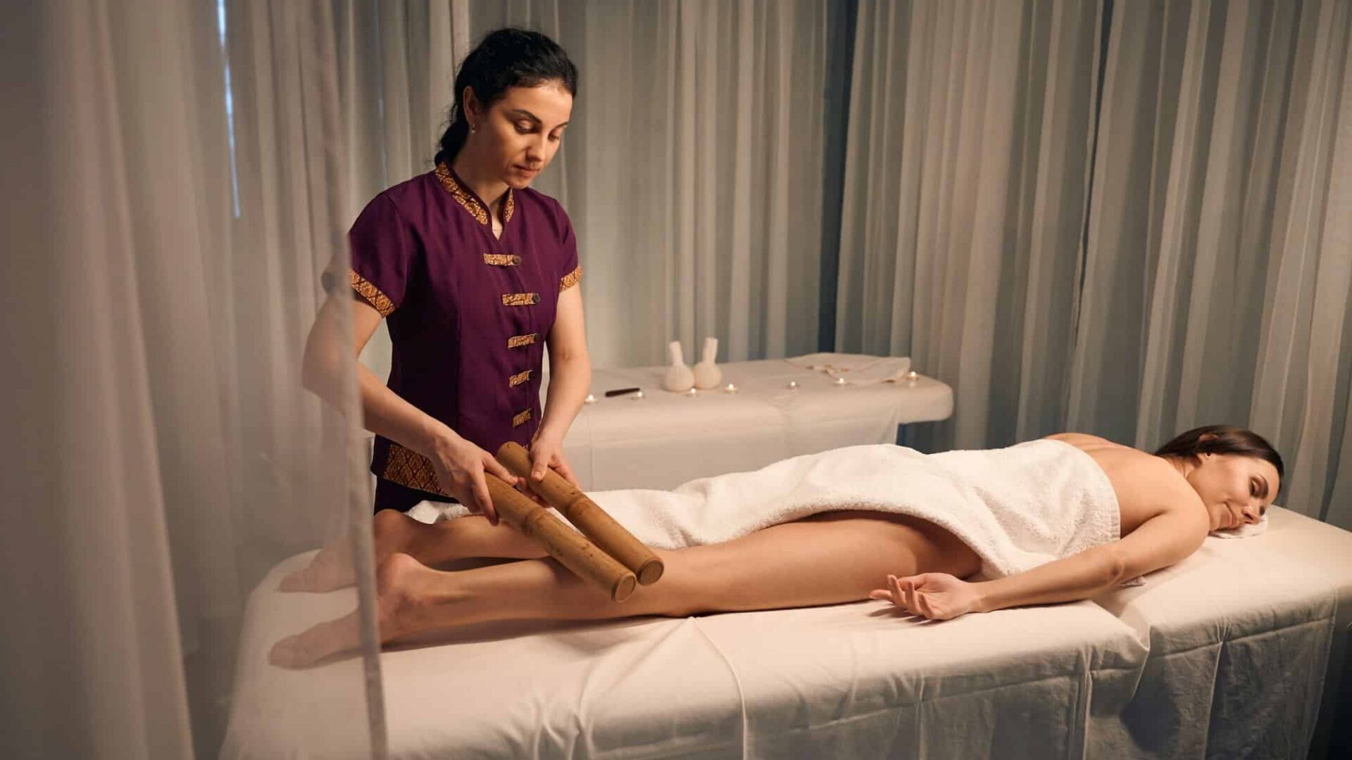 Experienced massotherapist giving leg massage to young woman