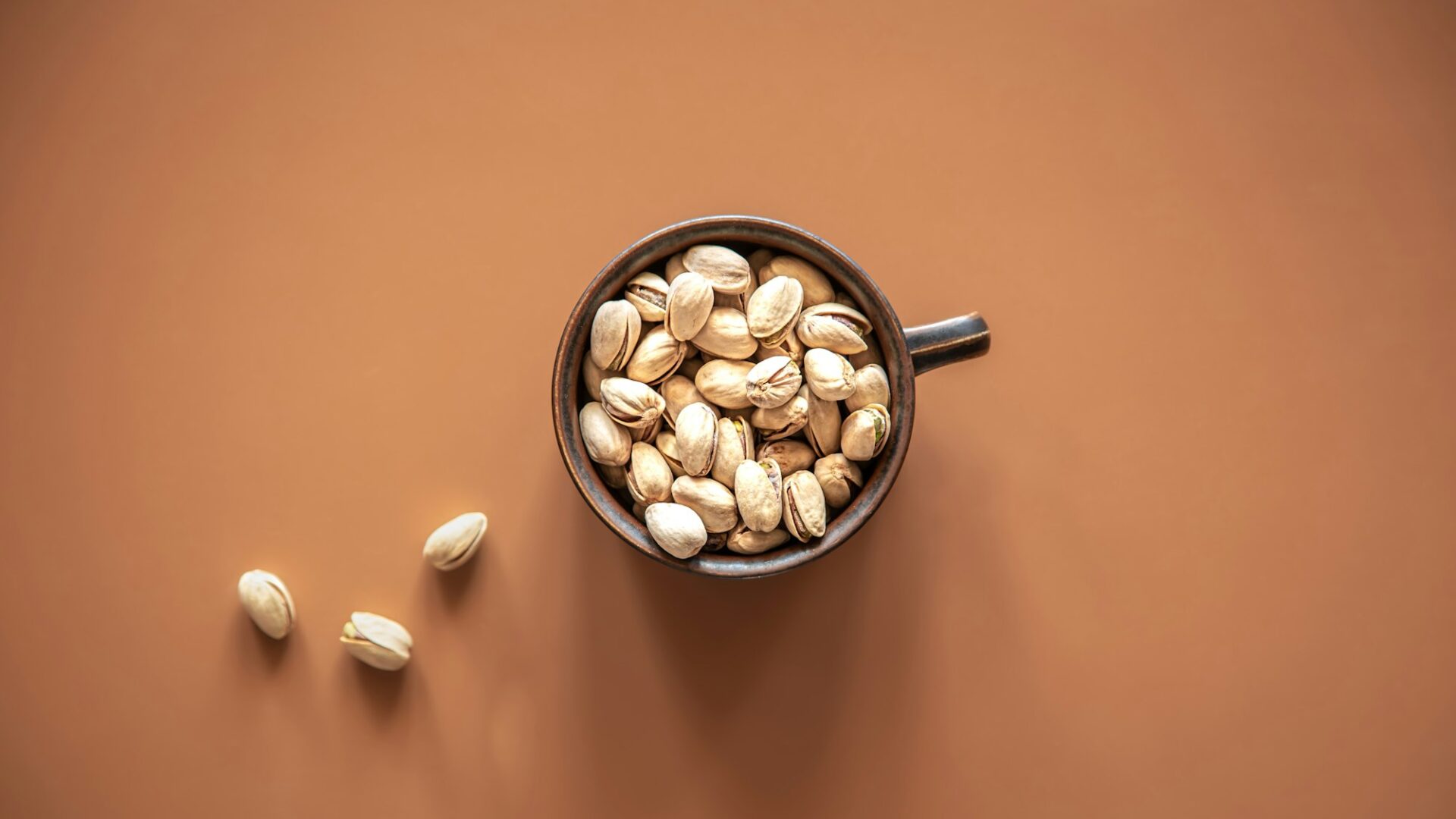 Flat lay, pistachios in a plate on a colored background.