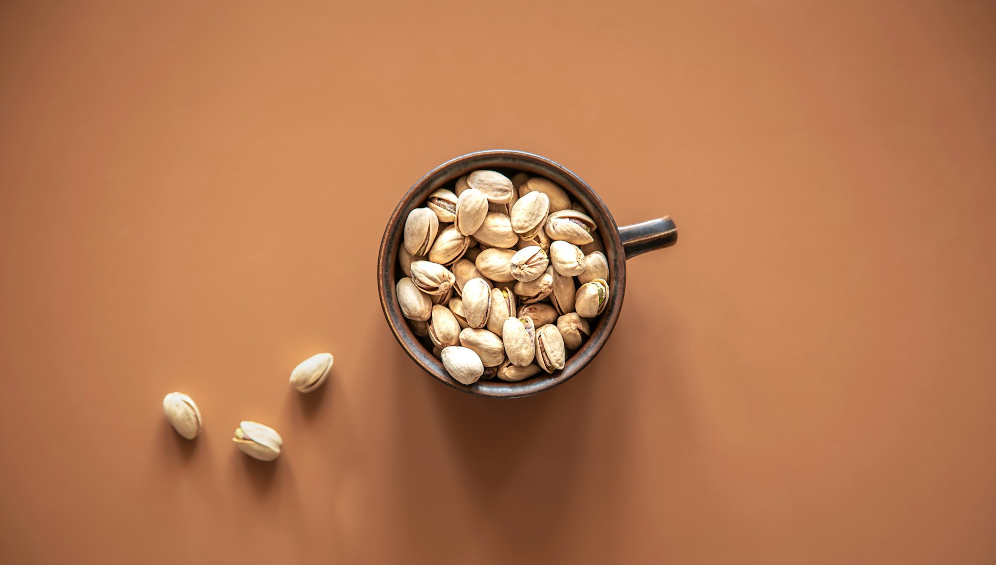 Flat lay, pistachios in a plate on a colored background.