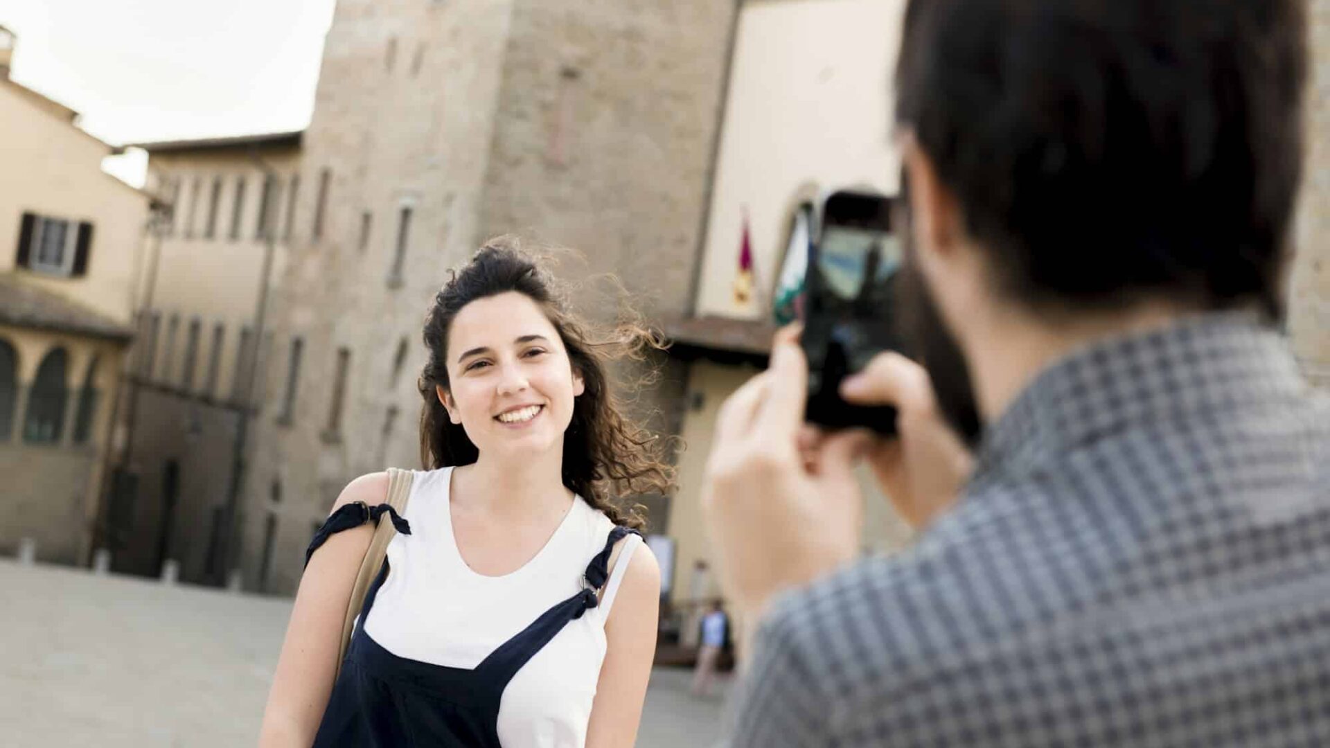 Over shoulder view of man photographing girlfriend by Arezzo Cathedral, Arezzo, Tuscany, Italy