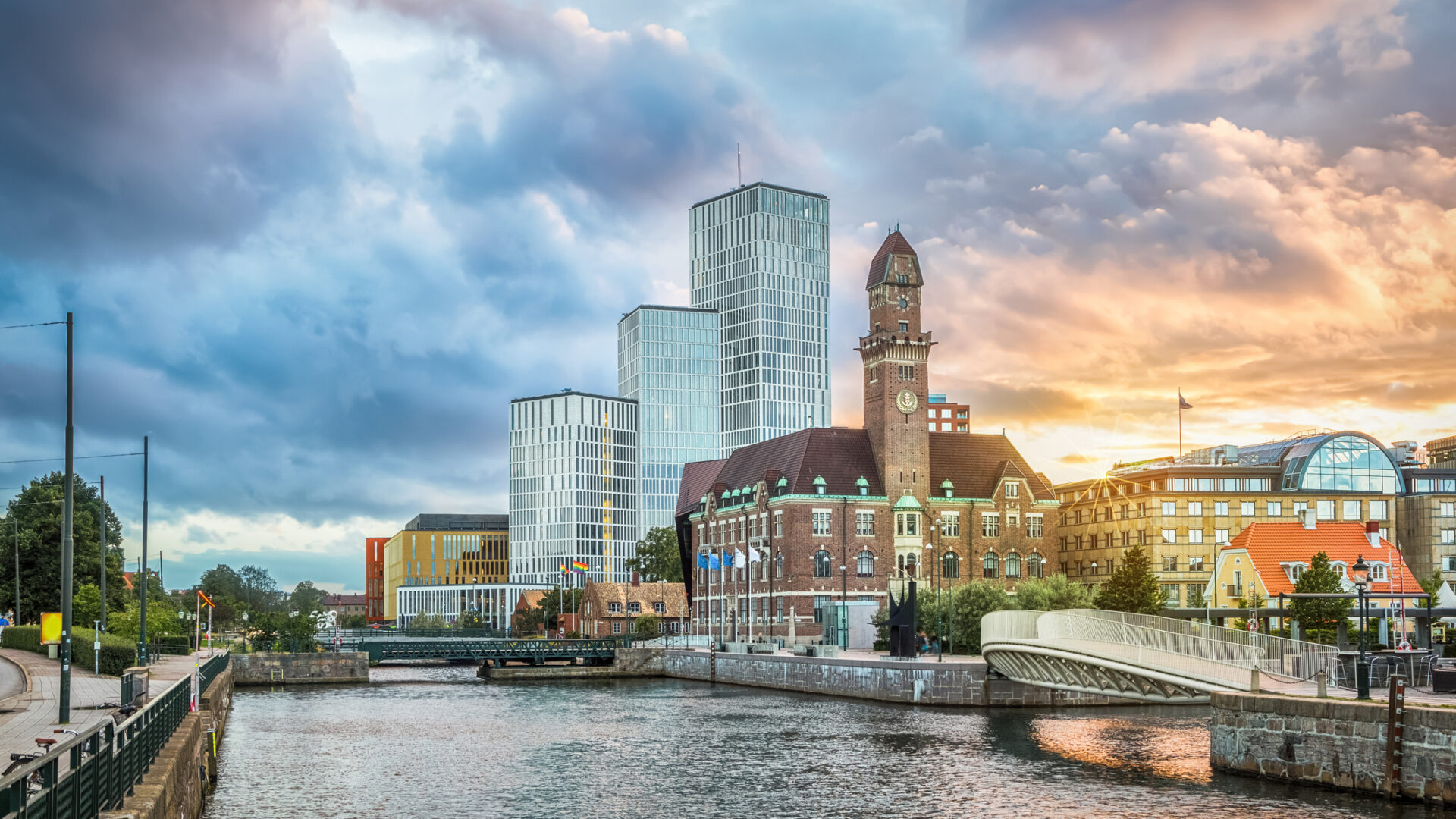 Ligne d'horizon urbaine à l'aube avec rivière et nuages.