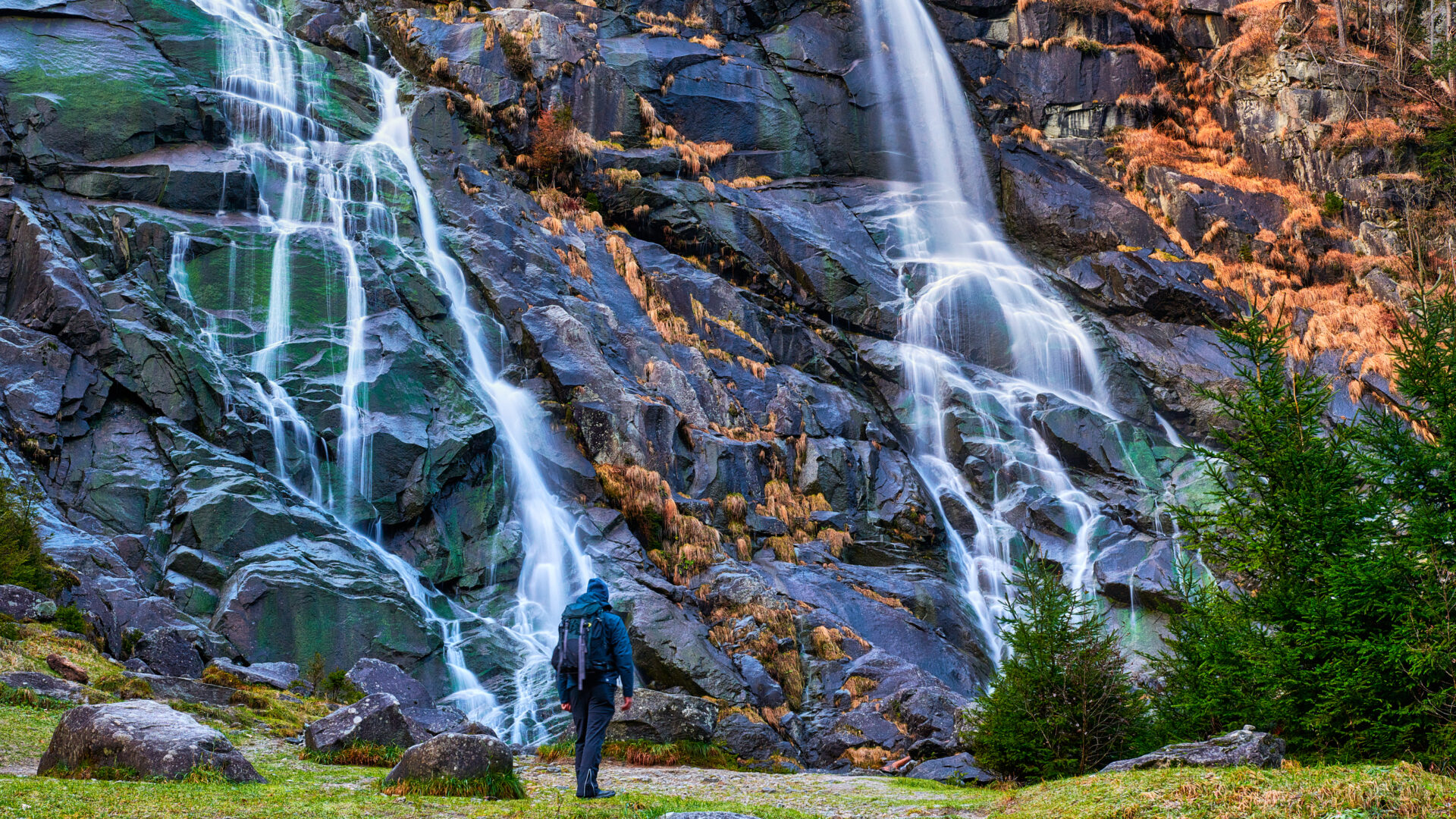 Senderista frente a una cascada de montaña.