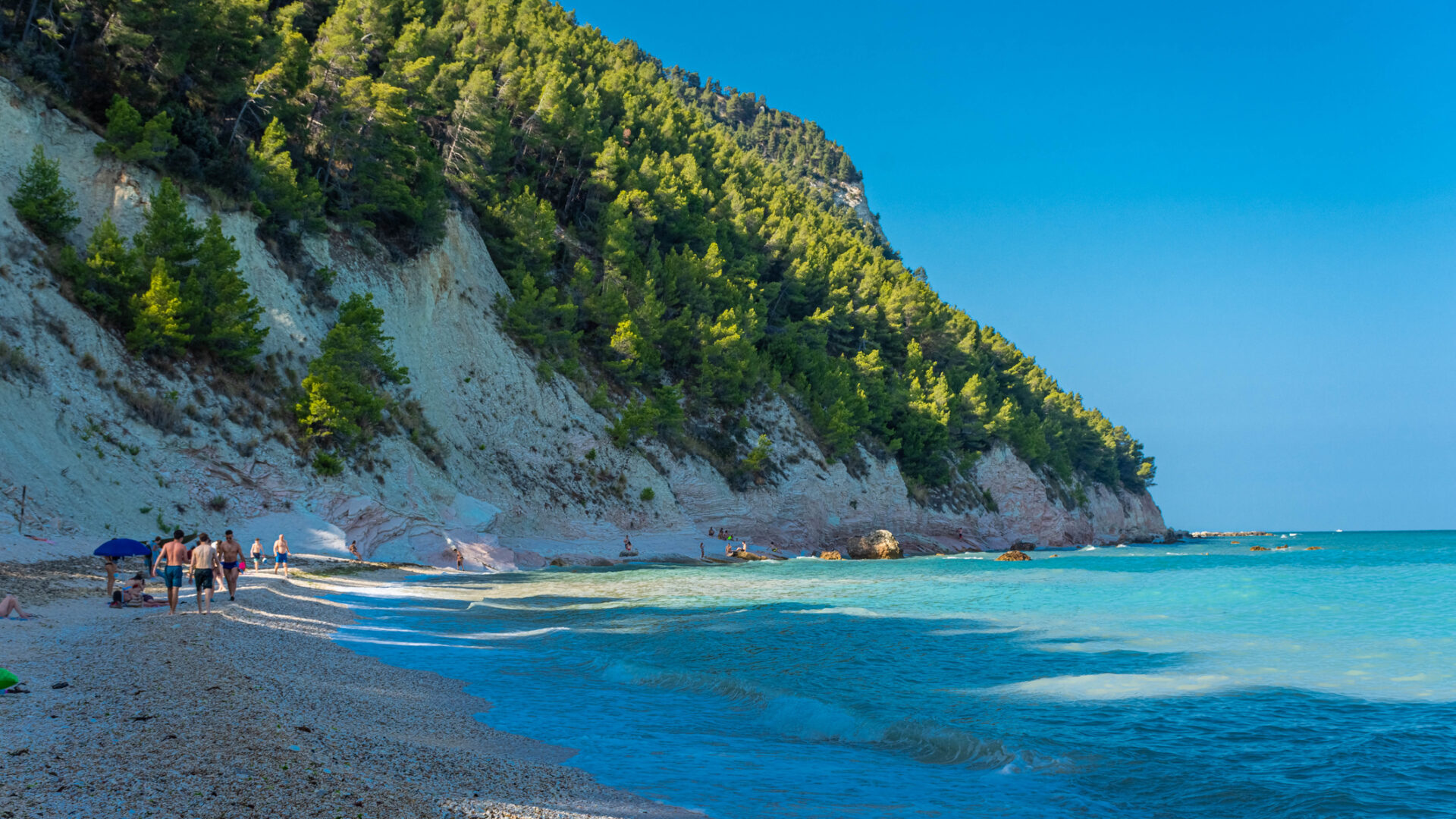 Beach with people and crystal clear sea.