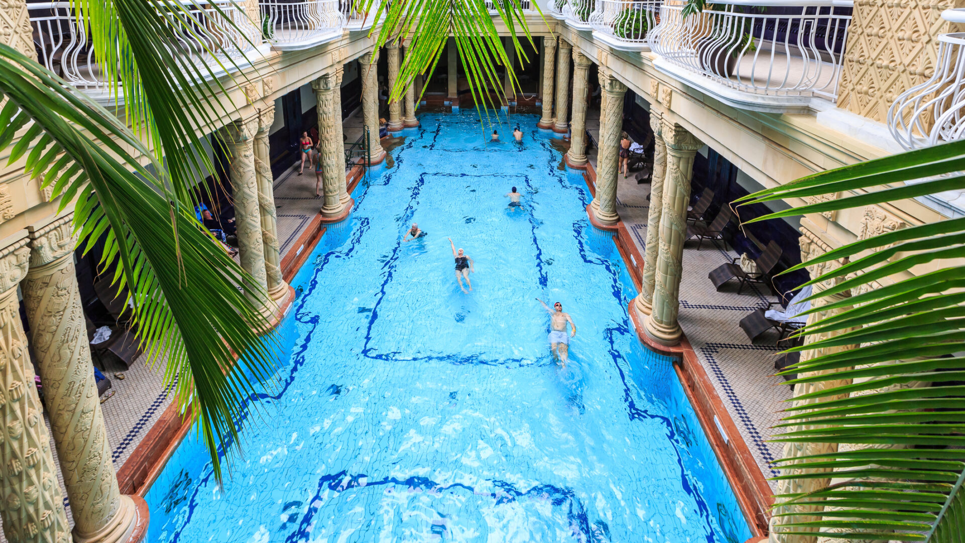Piscina interna di lusso con colonne e persone.