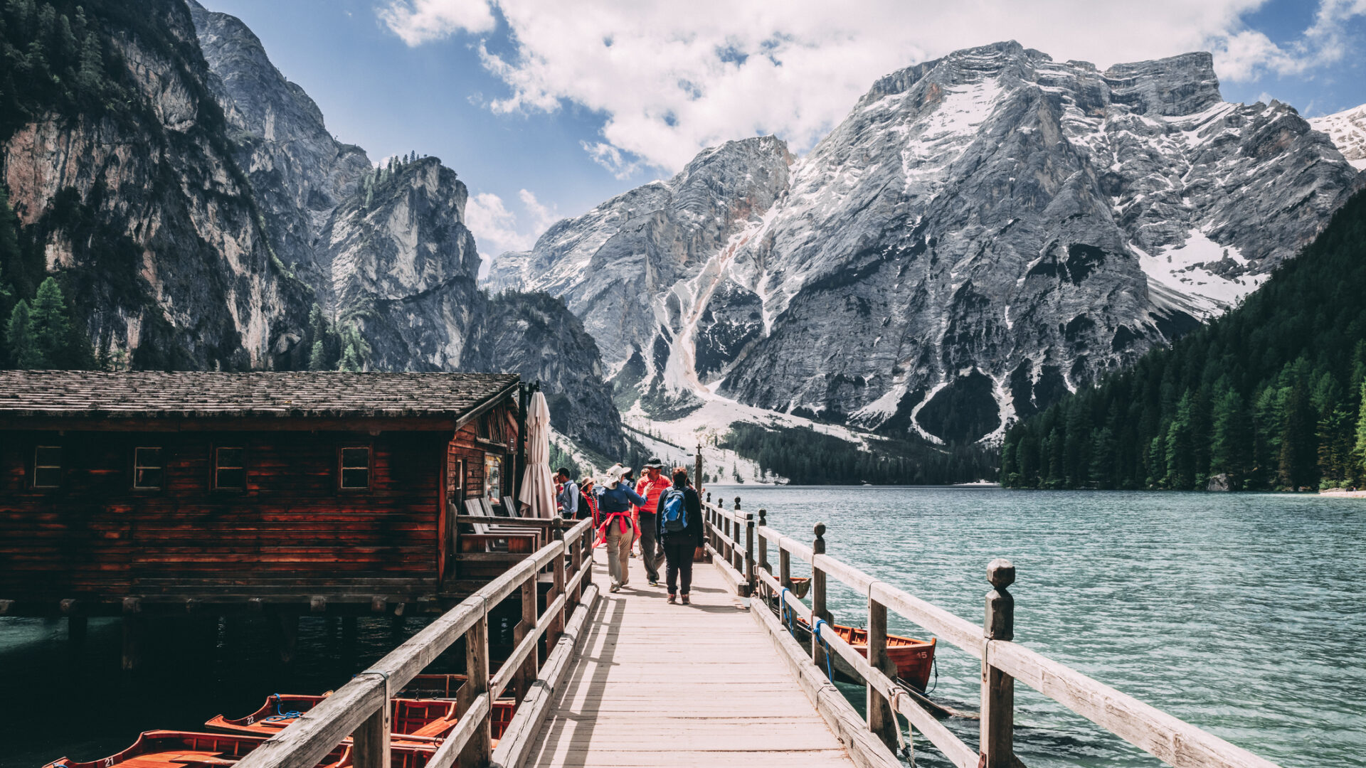 Ponte in legno sul lago montano con persone.