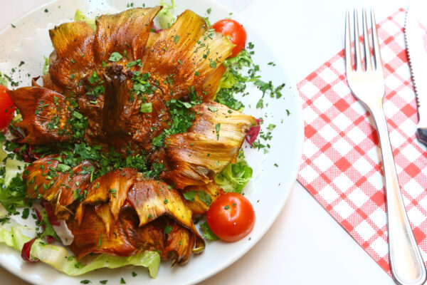 Alcachofas fritas con verduras y tomates cherry.
