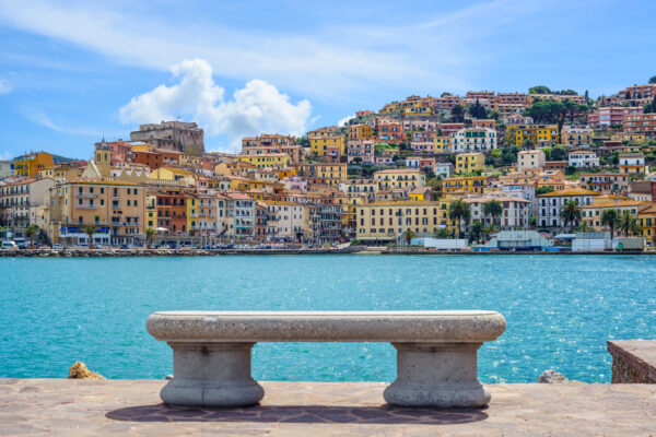 Banc face à la mer, maisons colorées en arrière-plan.