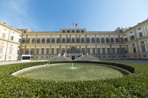 Palais historique avec fontaine centrale et drapeau italien.