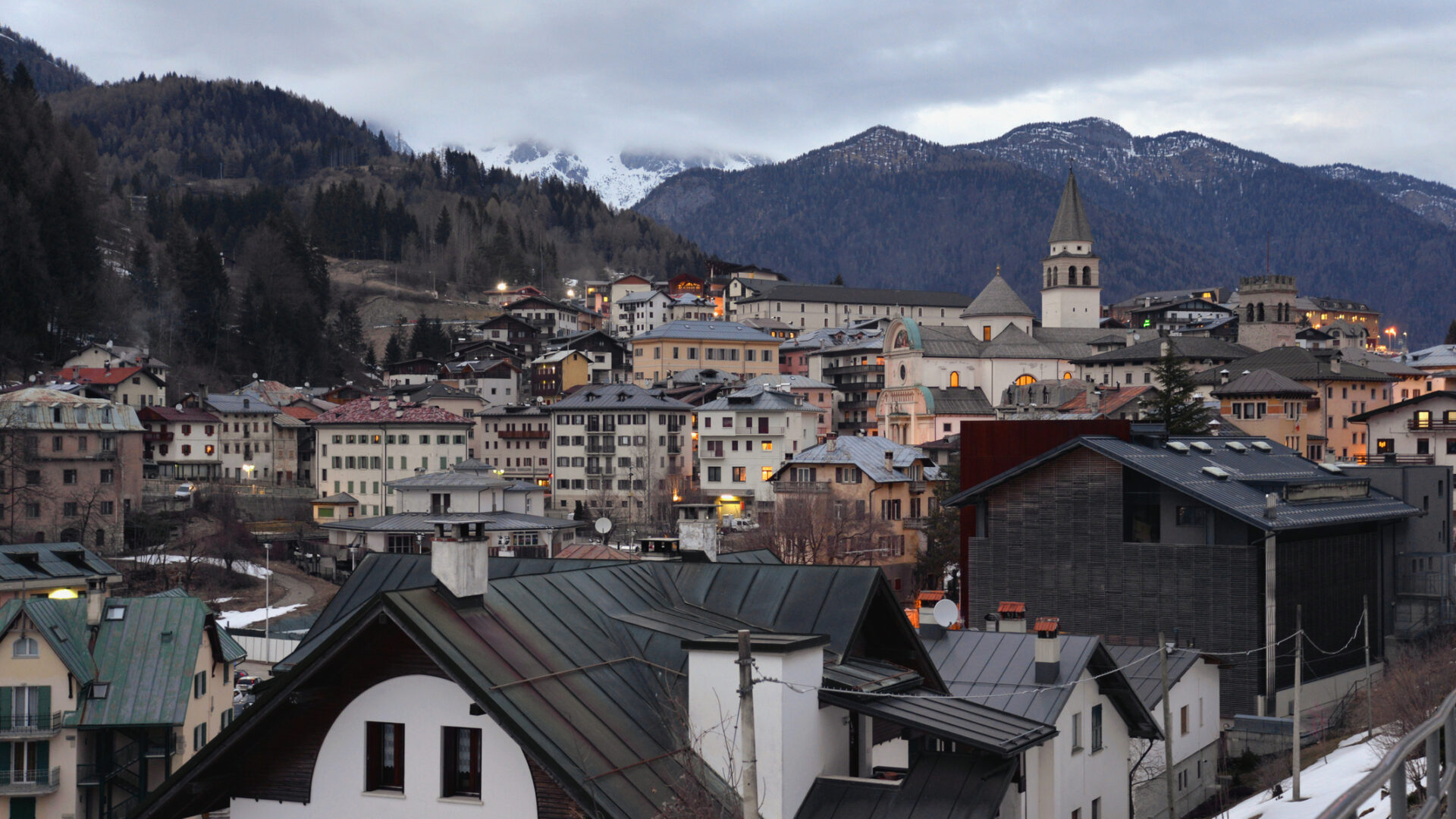 Bergdorf in der Abenddämmerung mit schneebedeckten Kirchen und Dächern