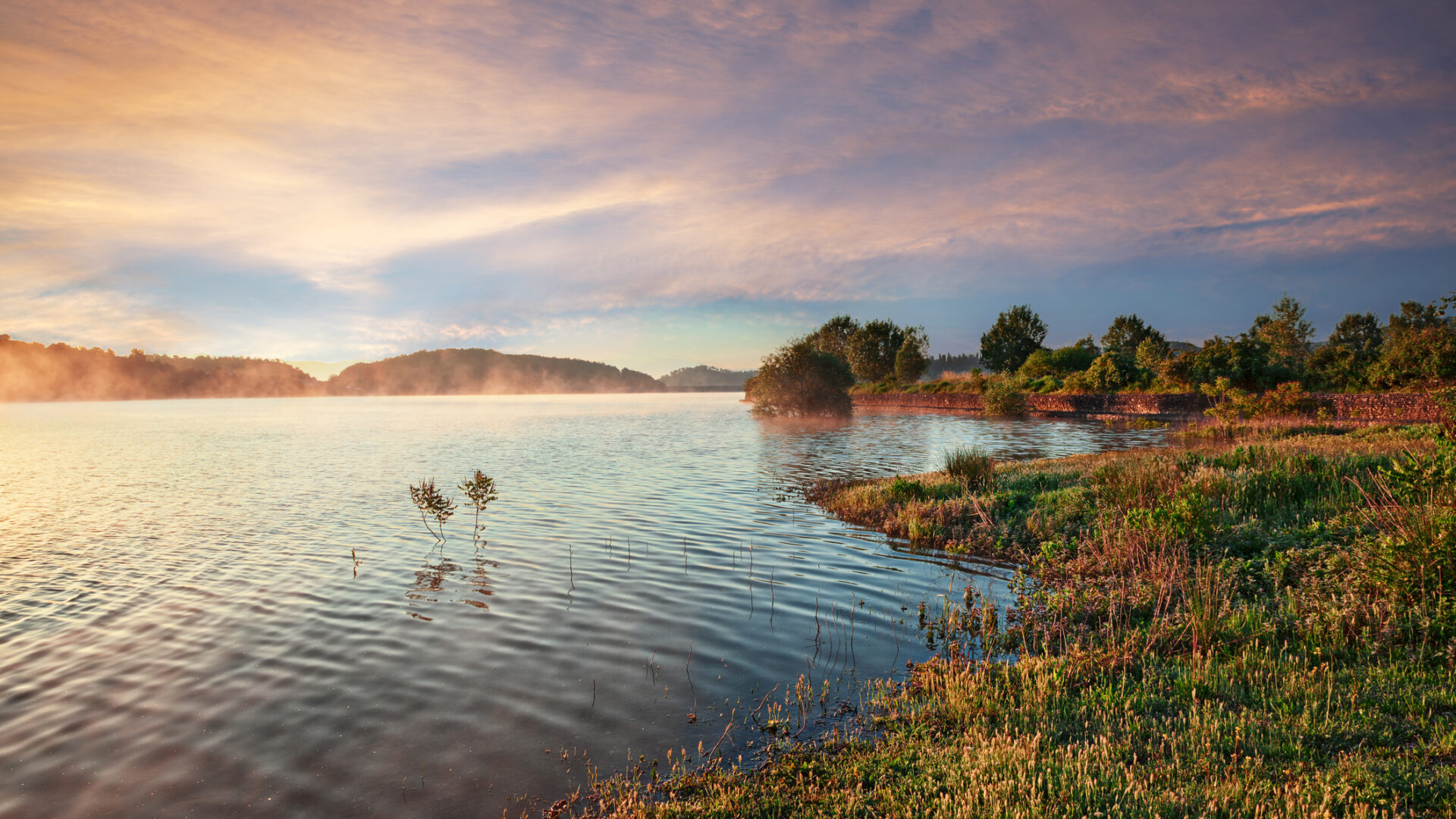 Nebelige Morgendämmerung über dem See mit farbigem Himmel