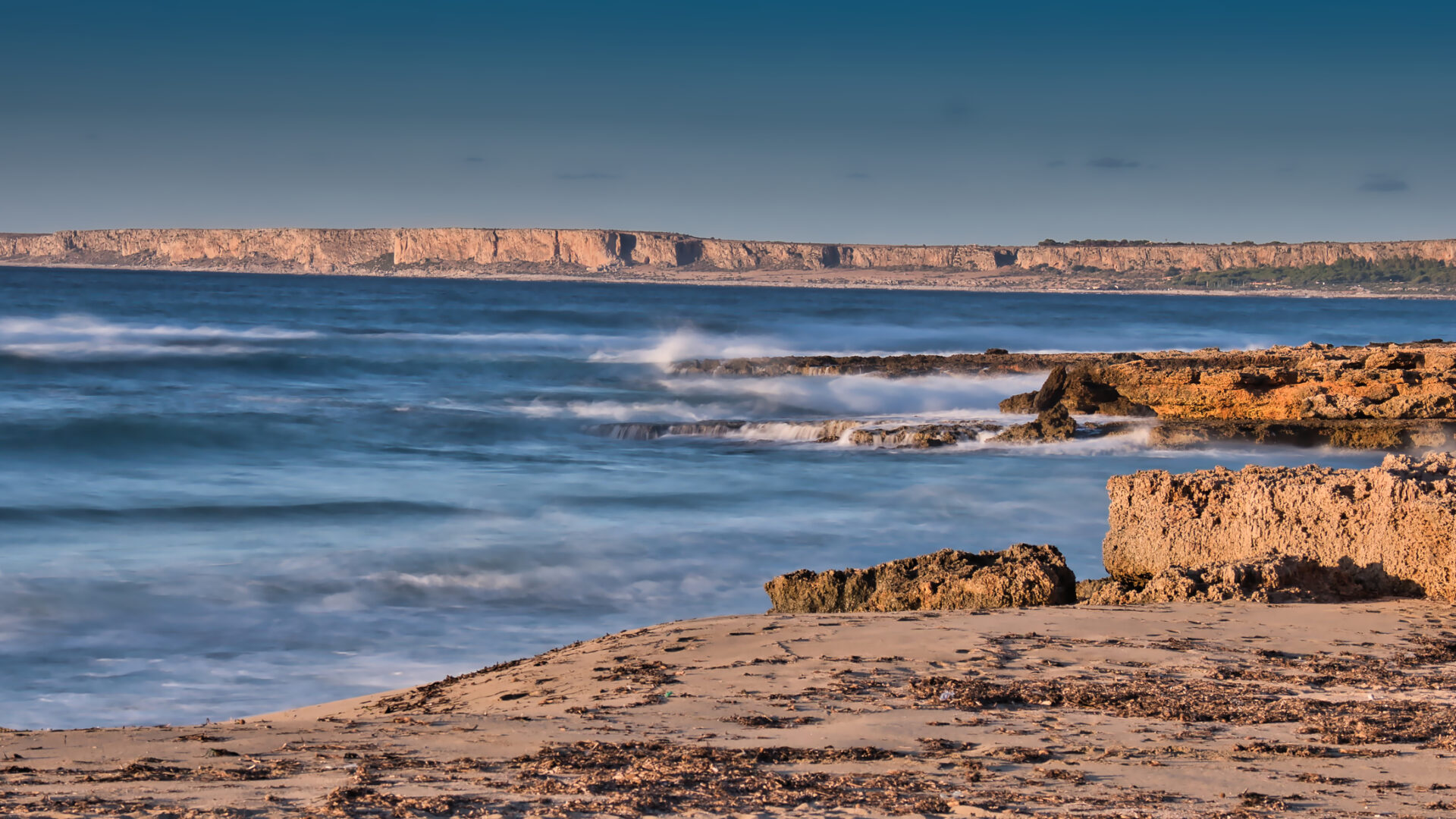 Costa rocciosa con mare mosso all'alba