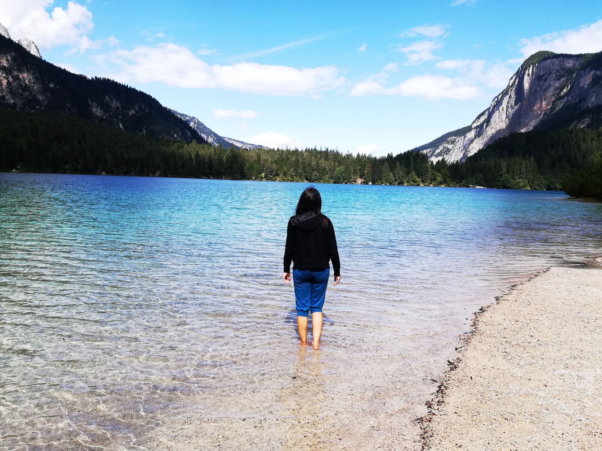 Persona cammina su riva lago montano