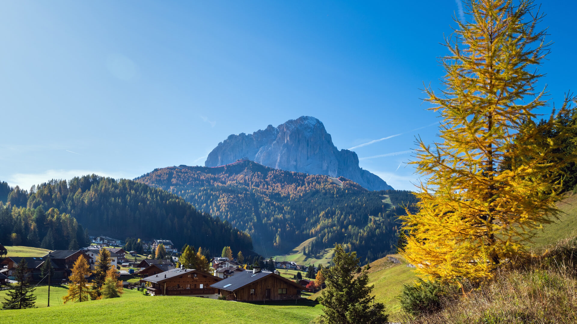 Villaggio montano autunnale con montagna imponente