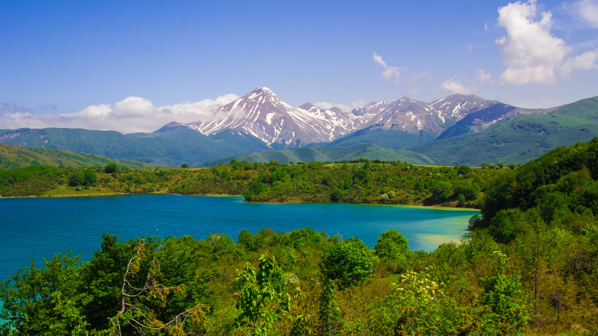 Lago montano circondato da montagne innevate e foreste