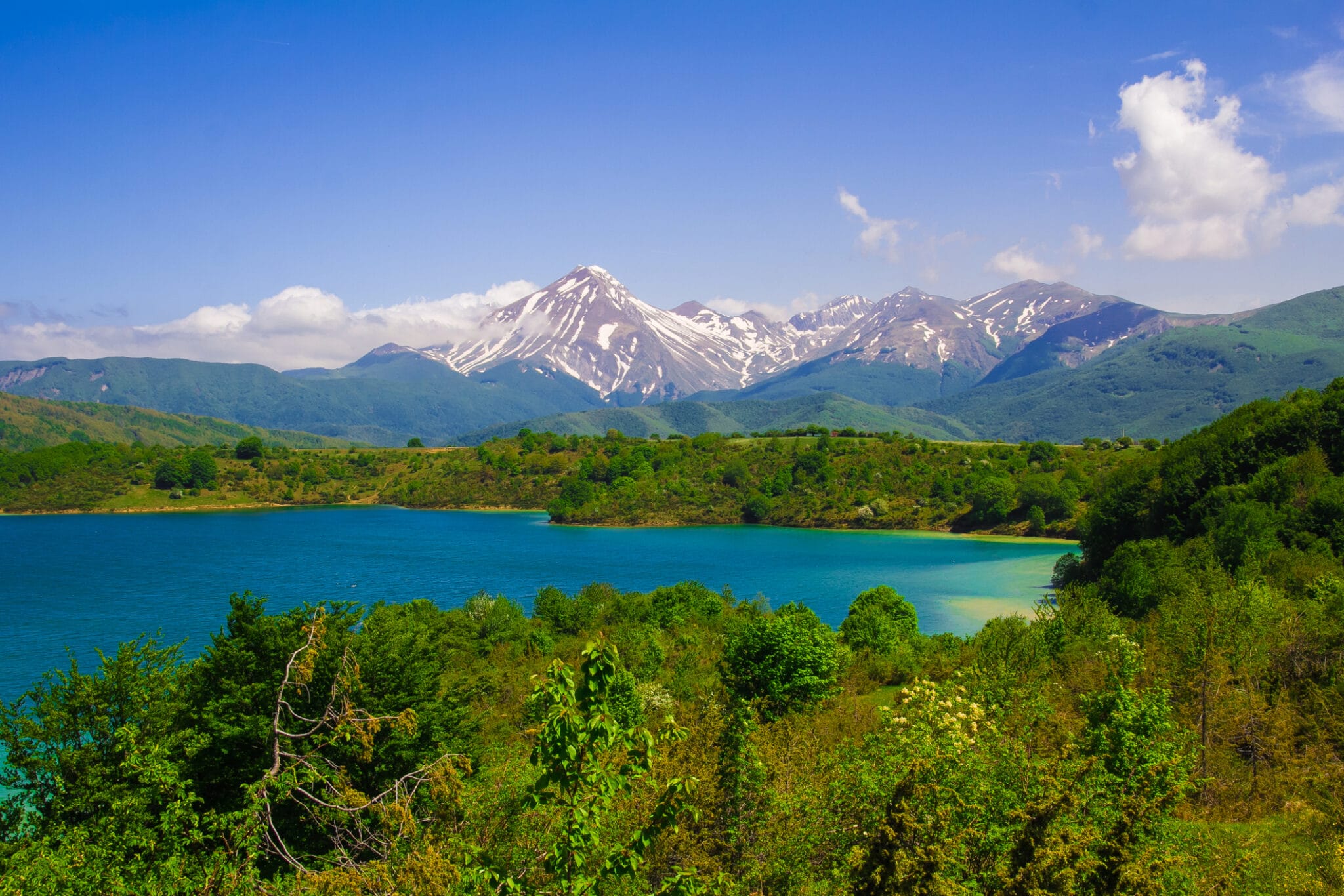 Lago montano circondato da montagne innevate e foreste