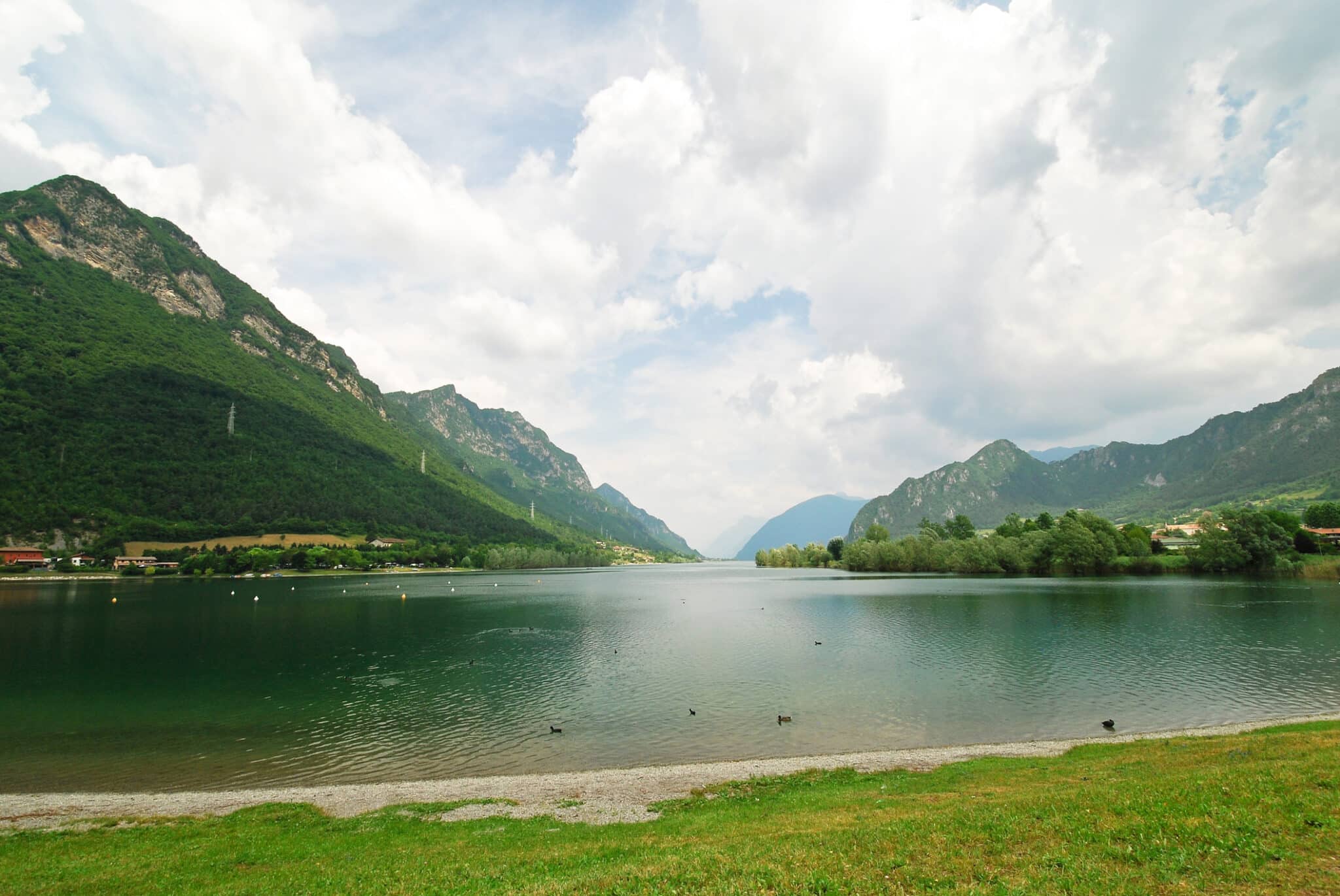 Lago sereno circondato da montagne verdi e cielo nuvoloso