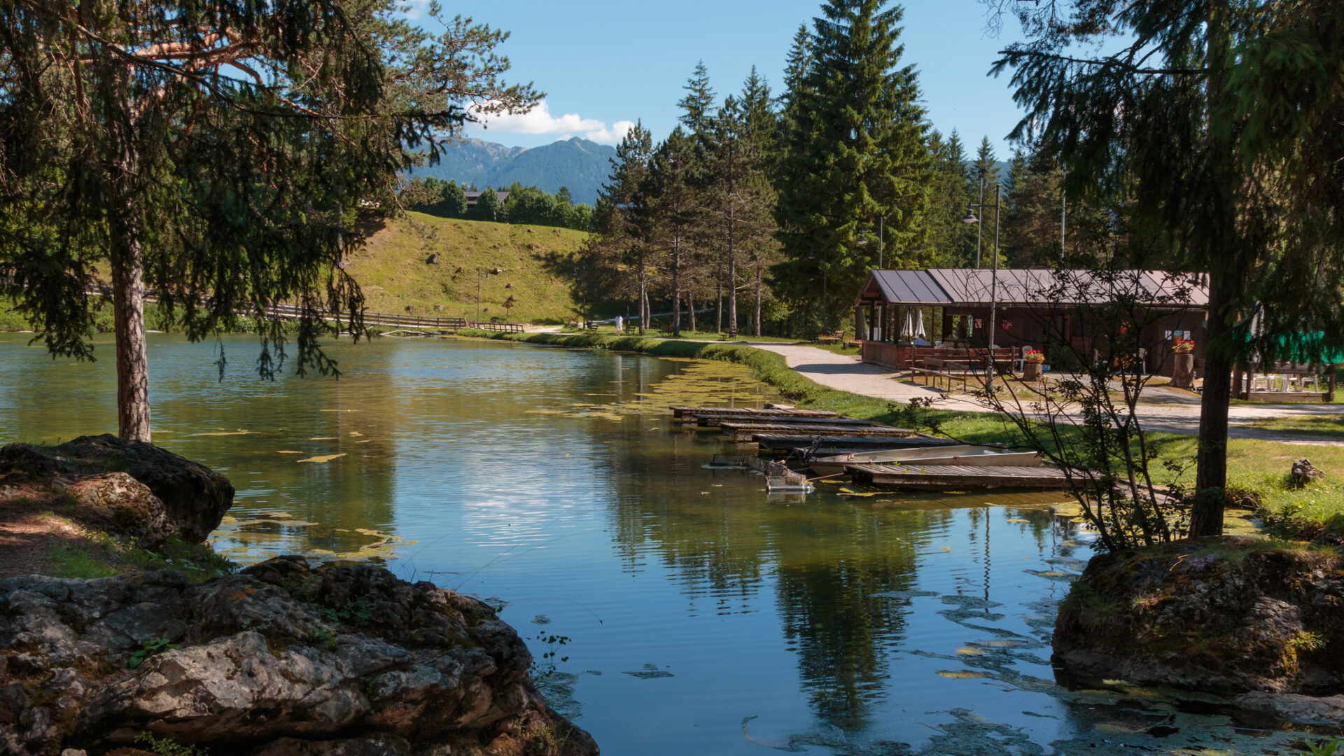 Lago montano con riflessi, alberi e capanna in legno
