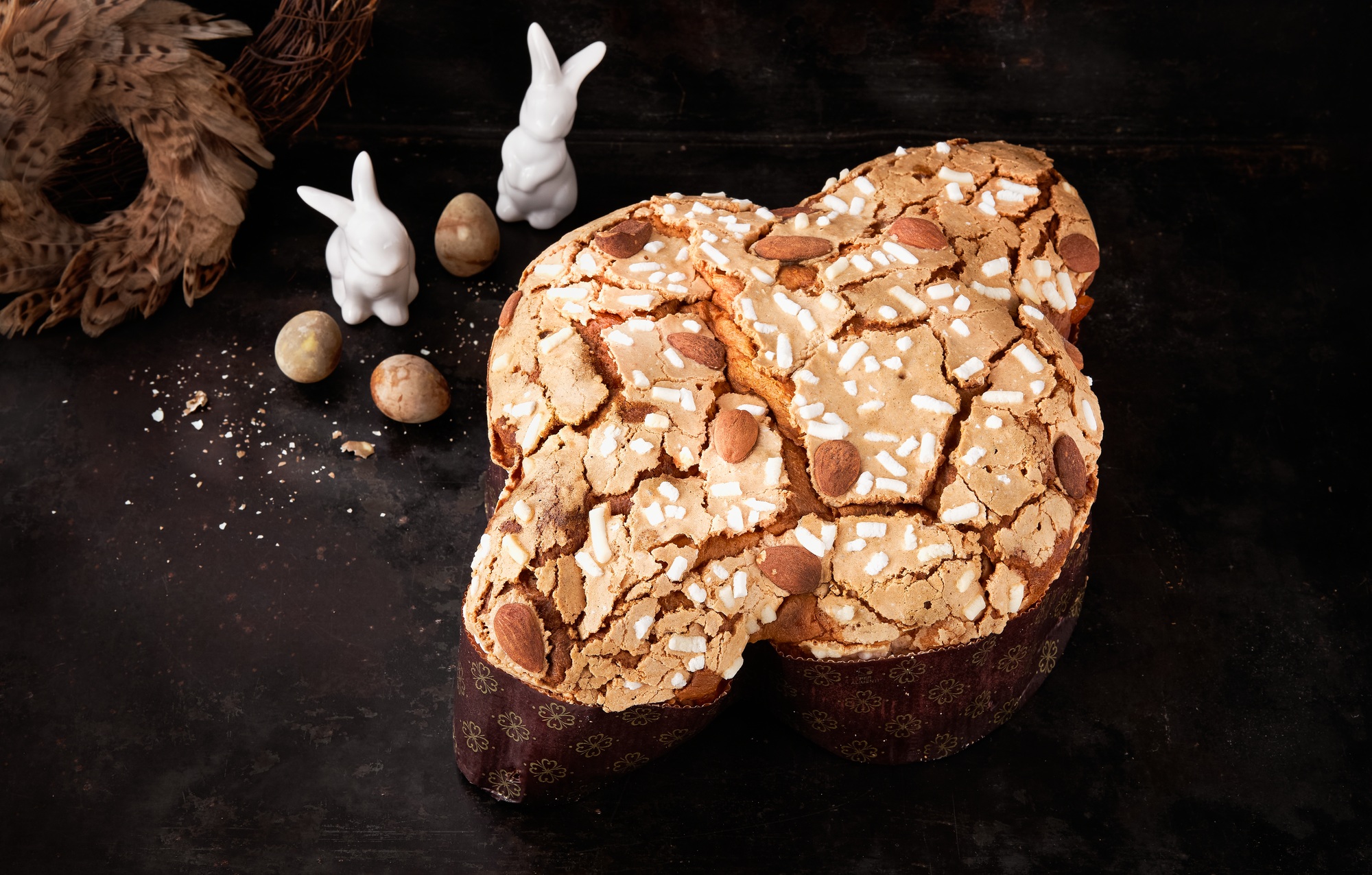 Colomba pasquale italiana con mandorle e granella di zucchero su sfondo scuro, dolce tradizionale di Pasqua.