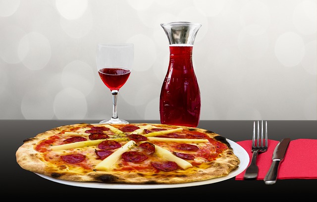 Pizza con salame e ananas, vino rosso in caraffa.