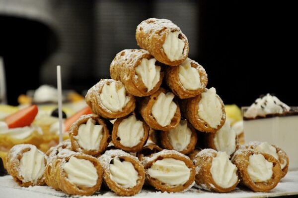 Piramide di cannoli ripieni con crema bianca.