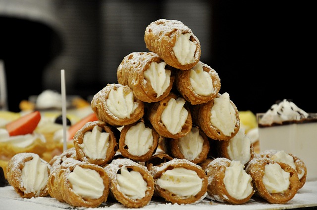 Piramide di cannoli ripieni con crema bianca.