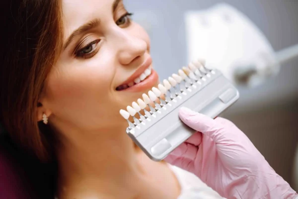 Dentista mostra campione colore denti paziente sorridente