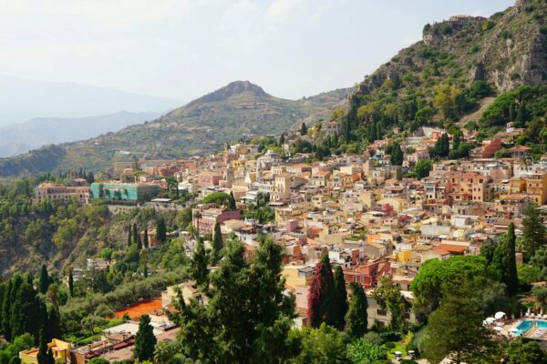 Vista panoramica di Taormina, colline verdi, case colorate.
