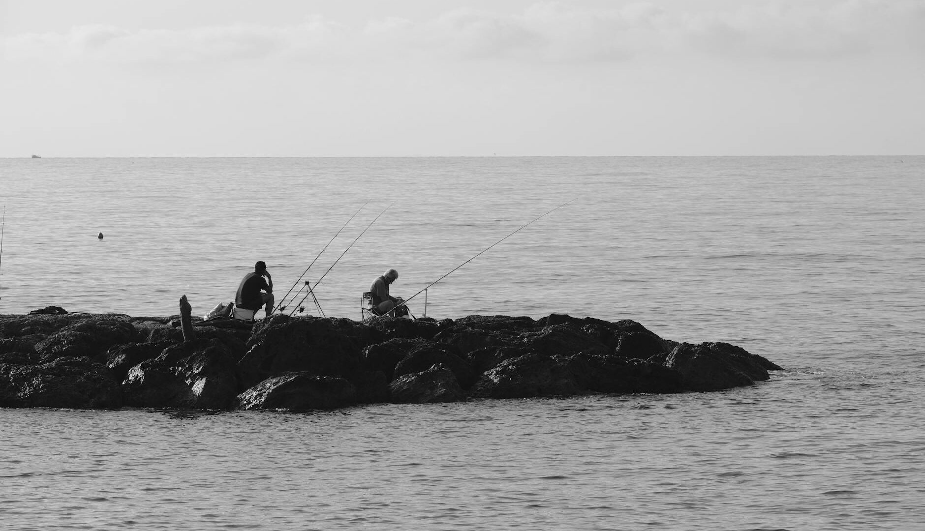 Pescatori su scogli in riva al mare.