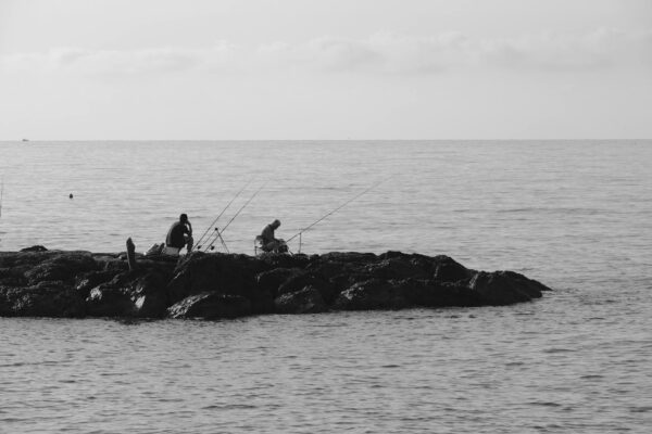 Pescatori su scogli in riva al mare.