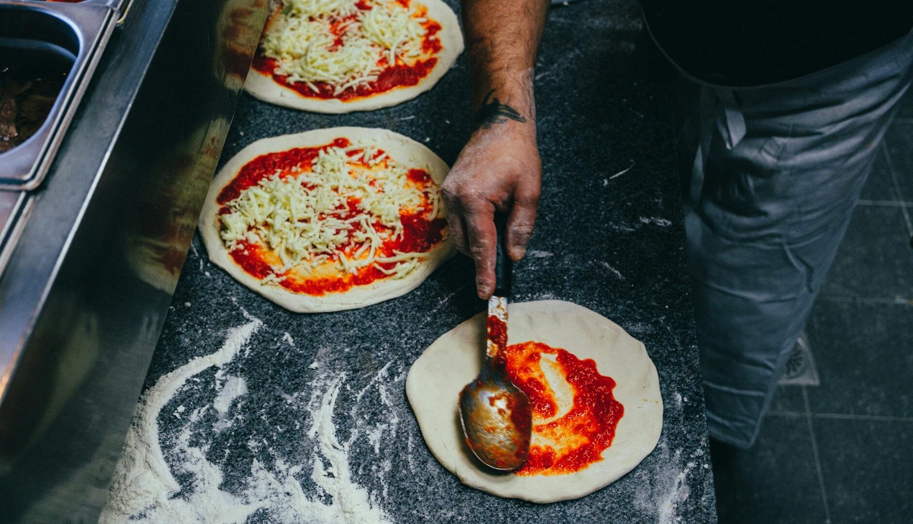 Preparazione artigianale di pizza con pomodoro e formaggio
