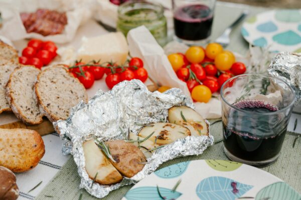 Picnic con pane, pomodori, patate e vino rosso.