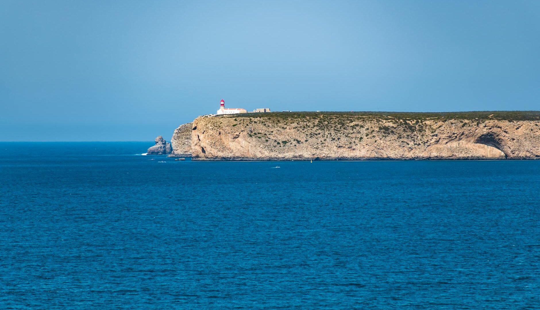 Faro su scogliera con mare azzurro