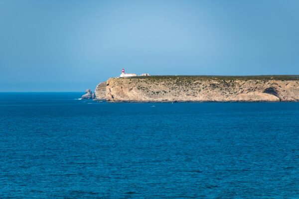 Faro su scogliera con mare azzurro