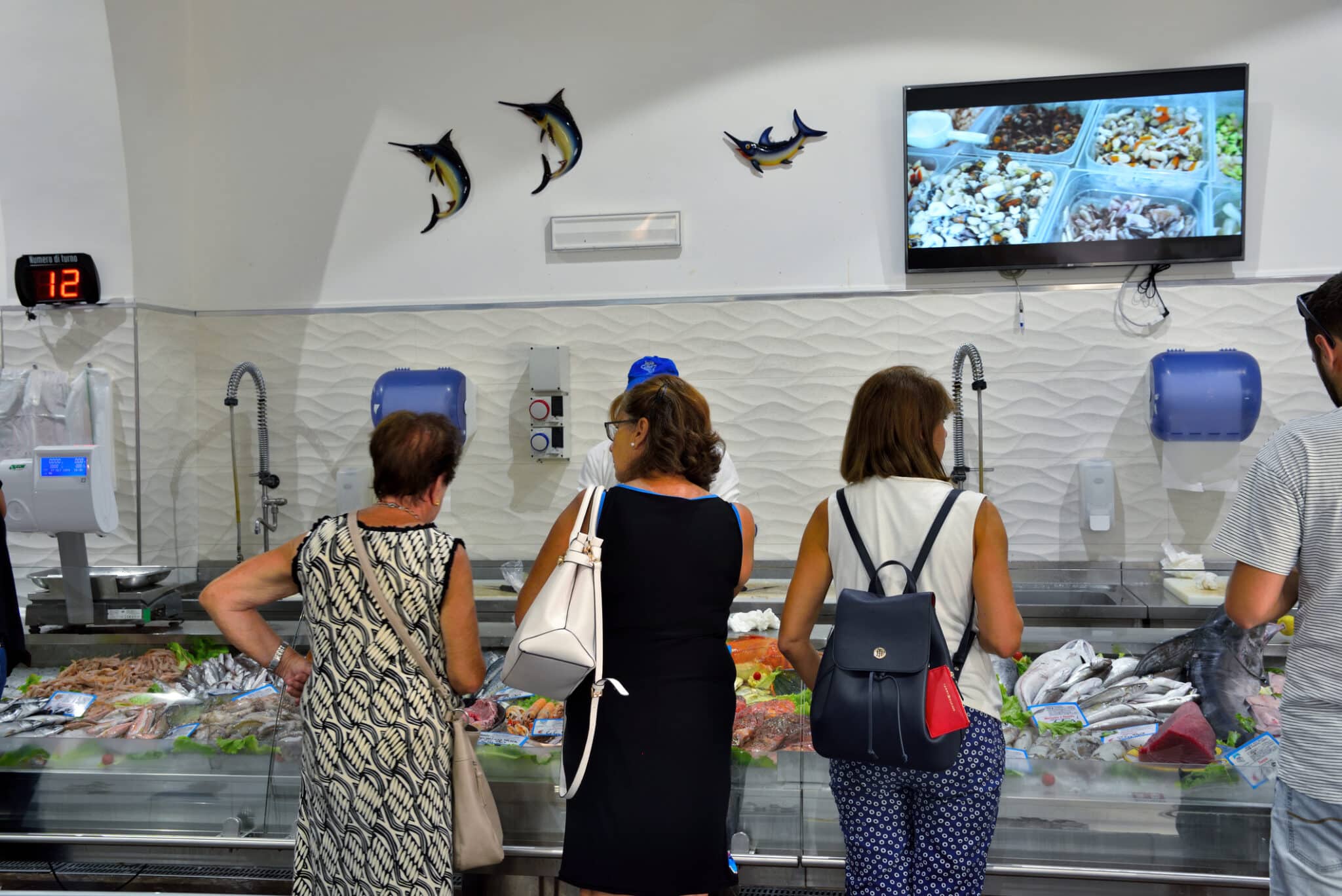 Clienti in attesa al banco pescheria.