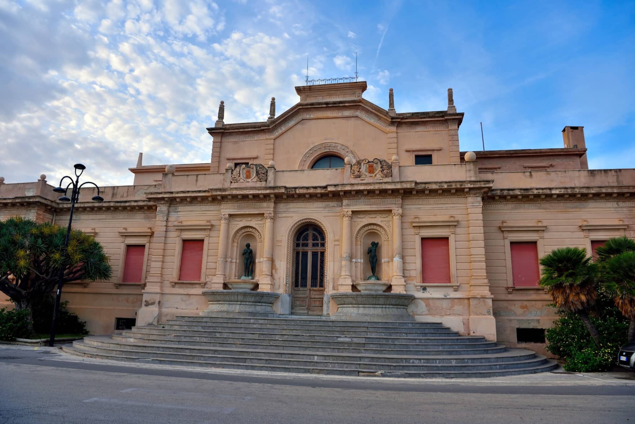 Facciata di un palazzo storico con scalinate e statue.