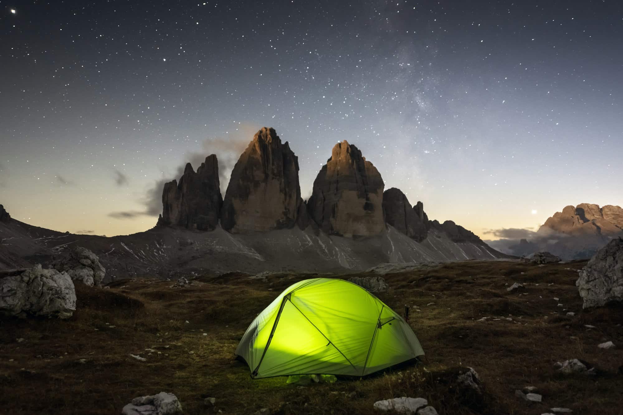Tenda verde illuminata dall'interno sullo sfondo di un incredibile cielo stellato