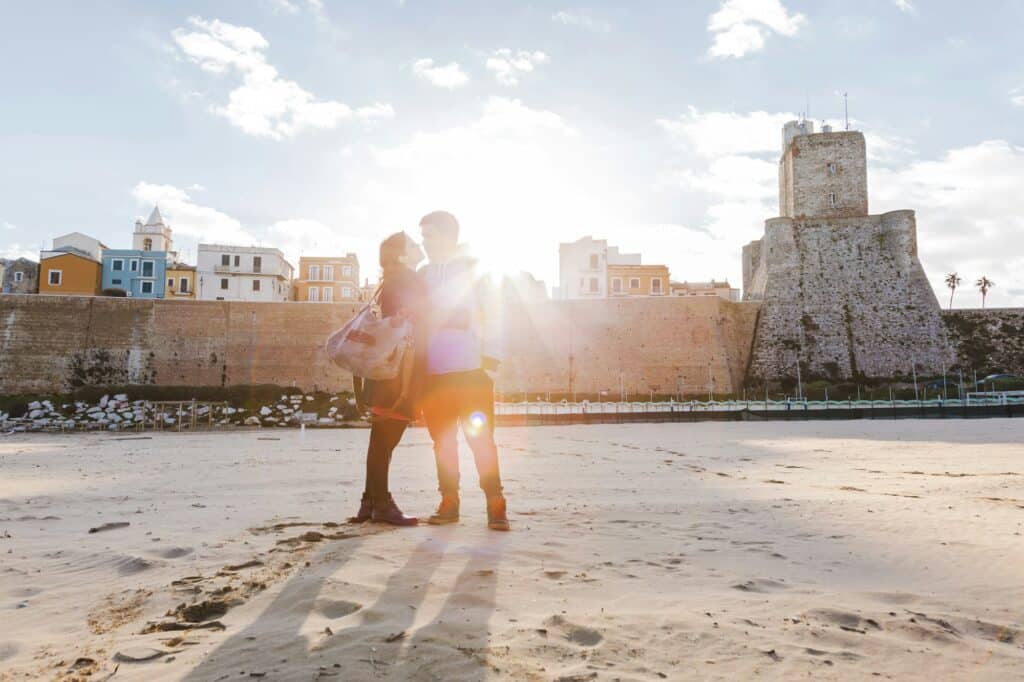 Italy, Molise, Termoli, young couple in the beach at sunrise