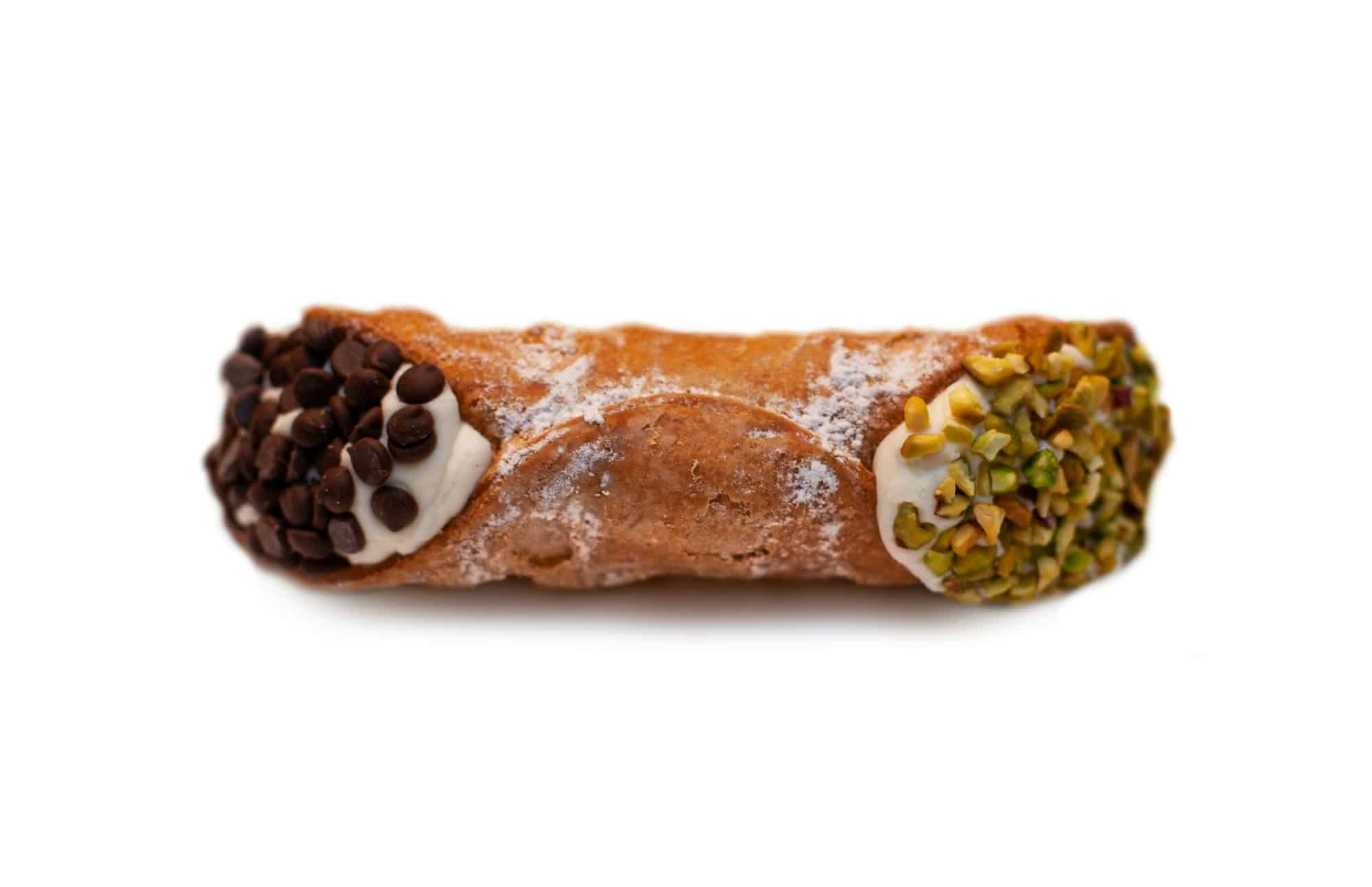 Cannoli siciliani con ricotta, cioccolato e pistacchi tritati isolati su fondo bianco.