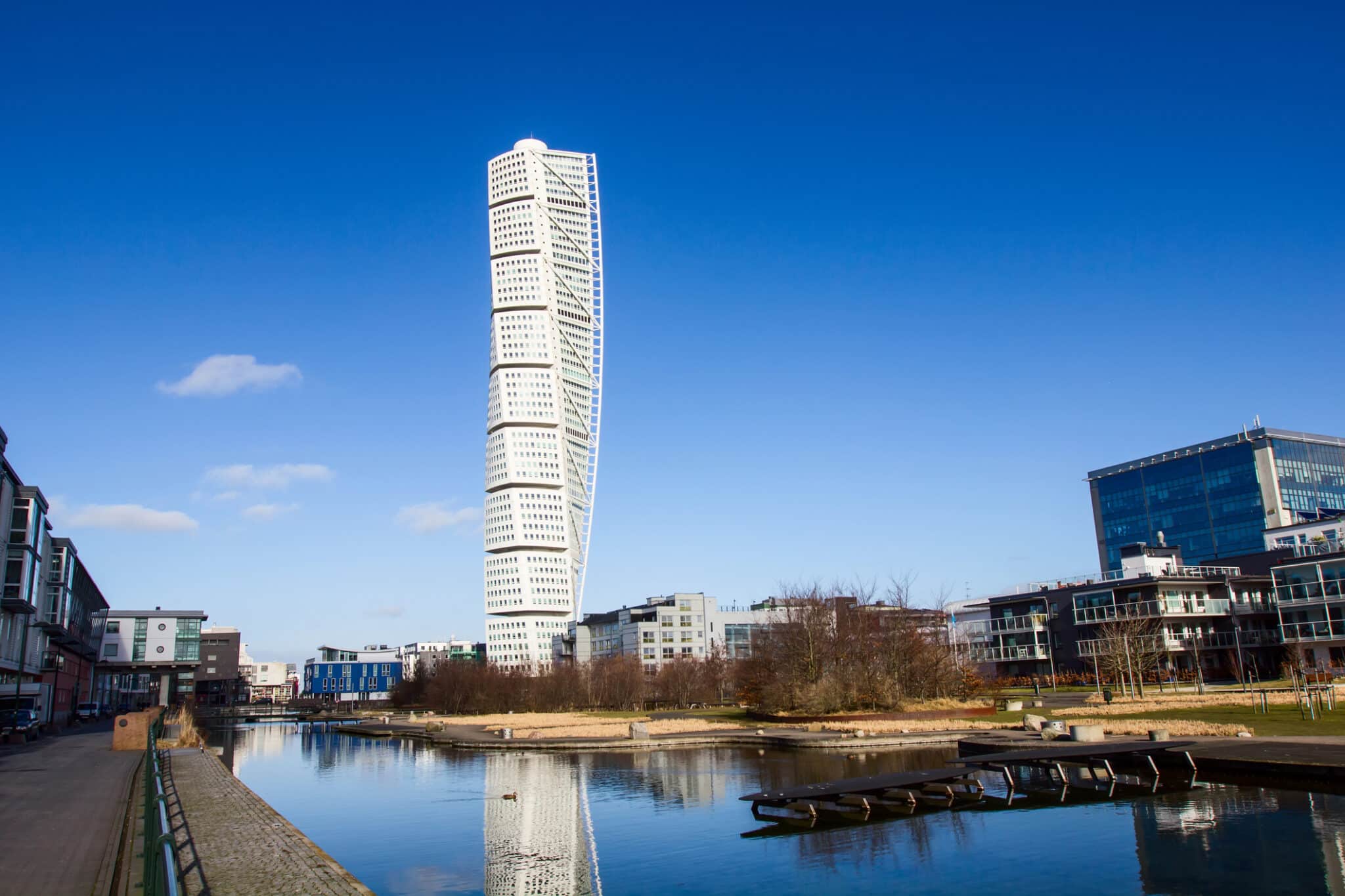 Gratte-ciel moderne se reflétant dans l'eau sous un ciel bleu.