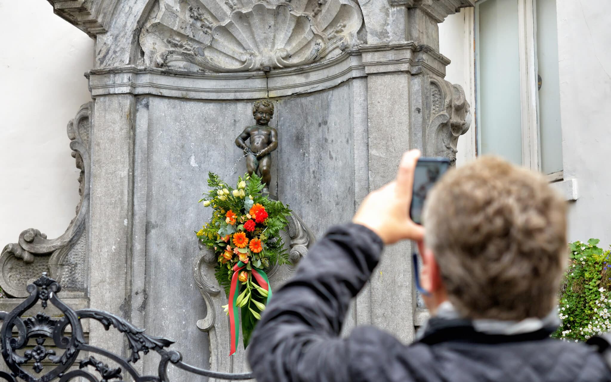 Persona fotografa Manneken Pis decorato a Bruxelles.