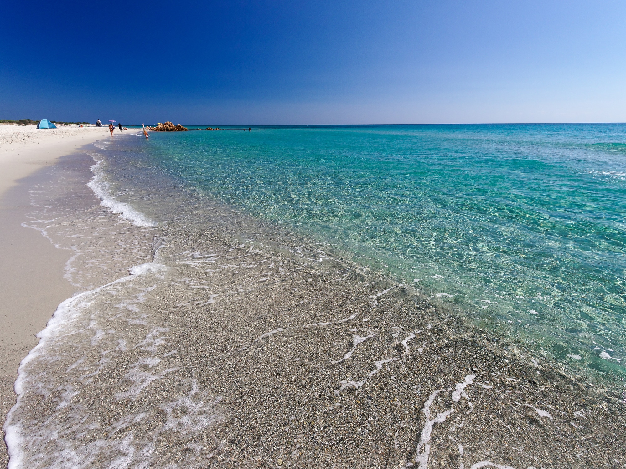 Spiaggia sabbiosa con mare cristallino.
