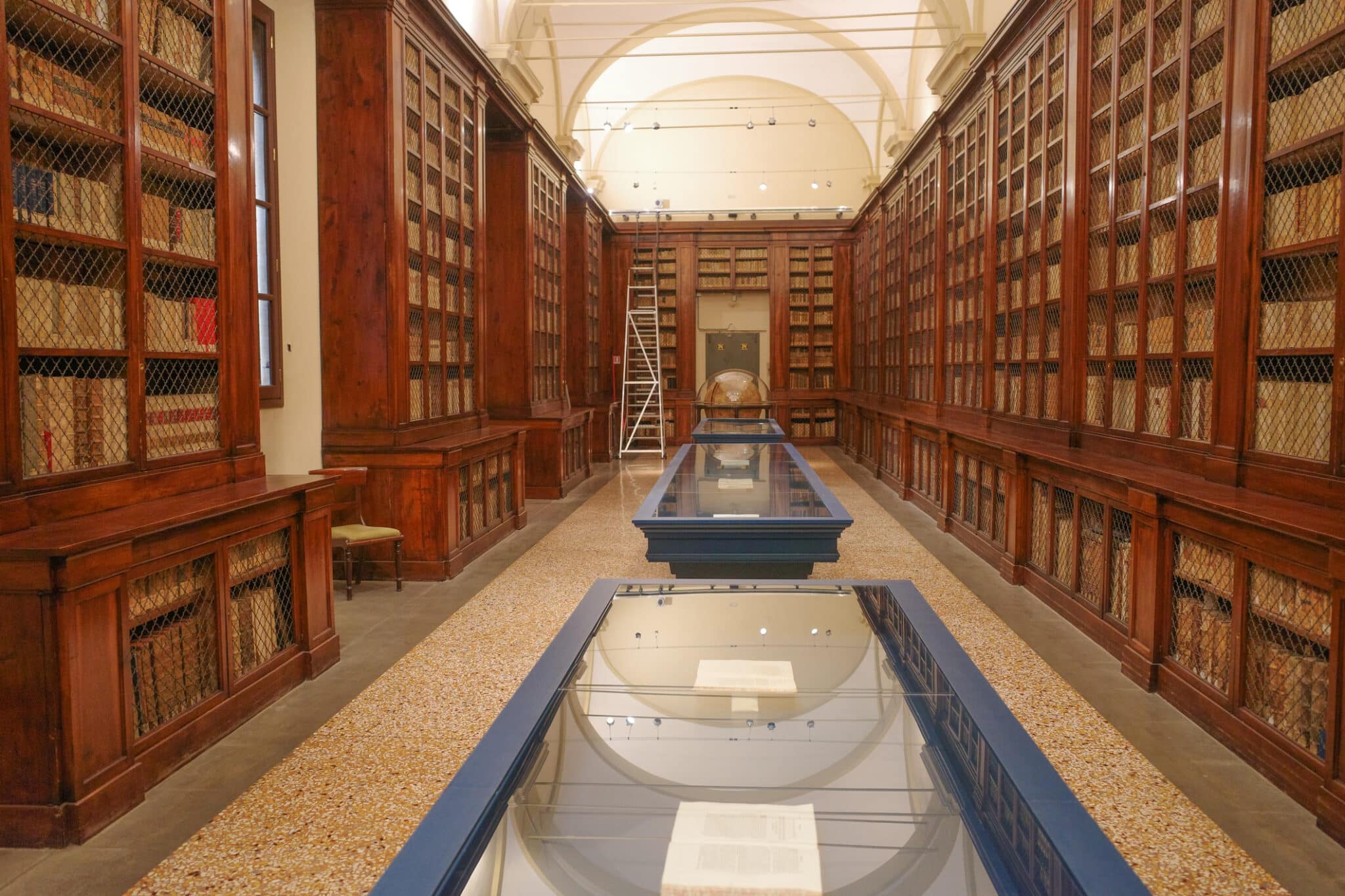Interno di antica biblioteca con scaffali in legno.
