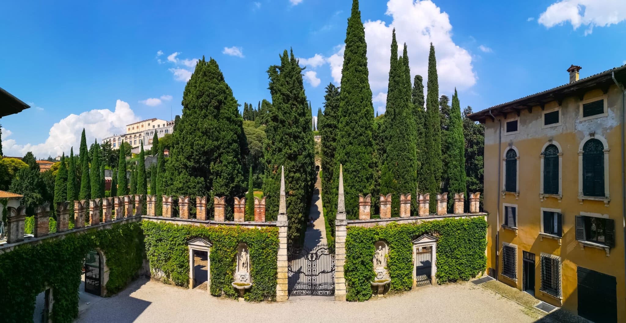 Giardino italiano con cipressi e villa storica.