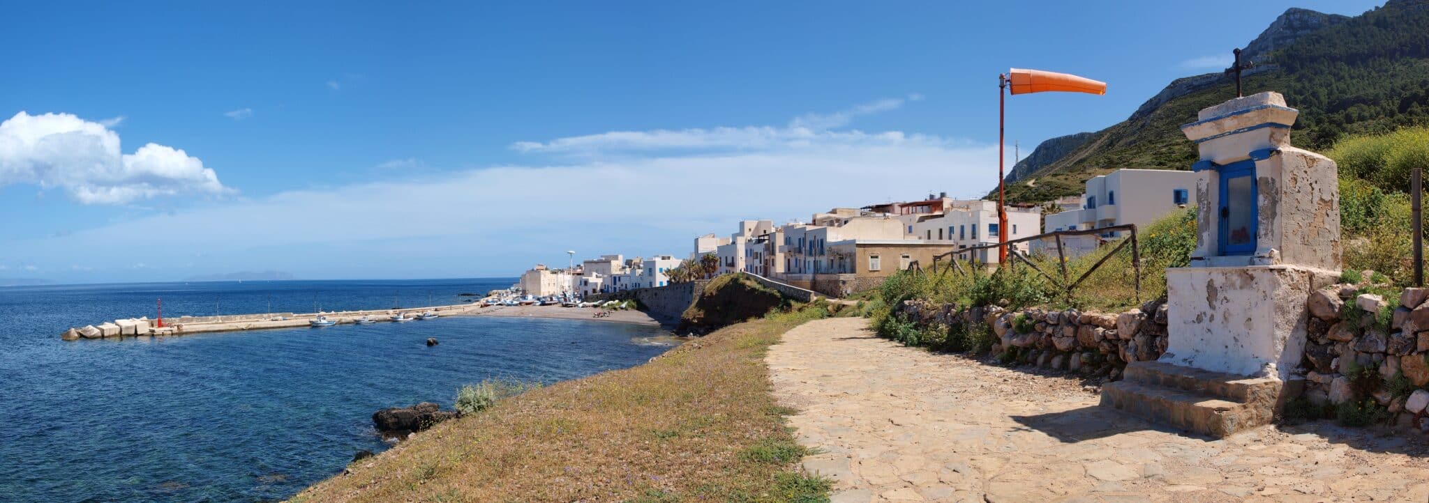 Paesino costiero mediterraneo sotto cielo azzurro.