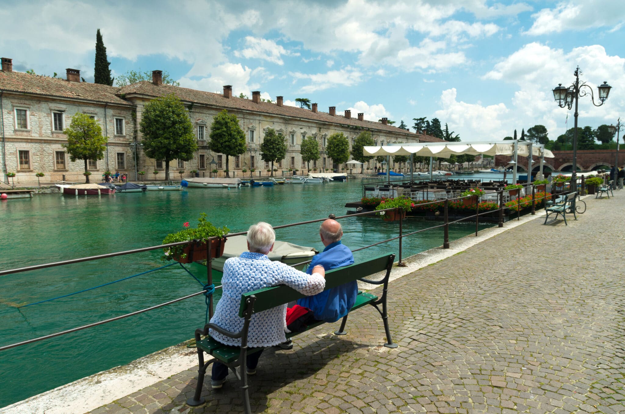 Due uomini anziani che si godono la vista nel pittoresco porto di peschiera del garda