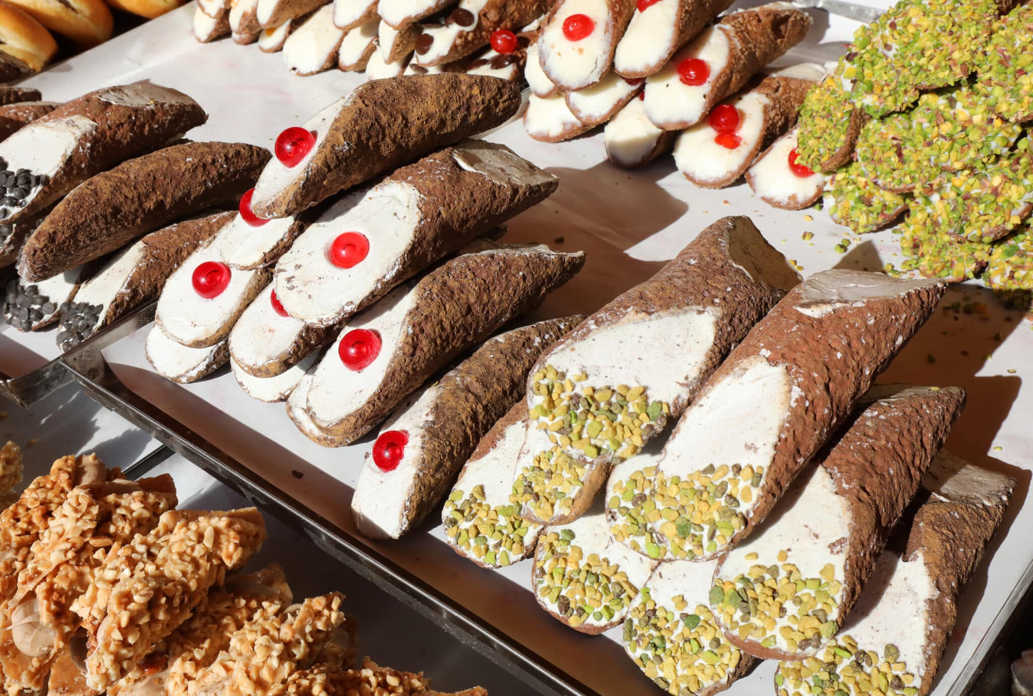 pasticcini con pistacchio e ciliegia in vendita nel pastr italiano. pasticcini con pistacchio e ciliegia in vendita nello stand di pasticceria chiamato Cannolo Siciliano in lingua italiana