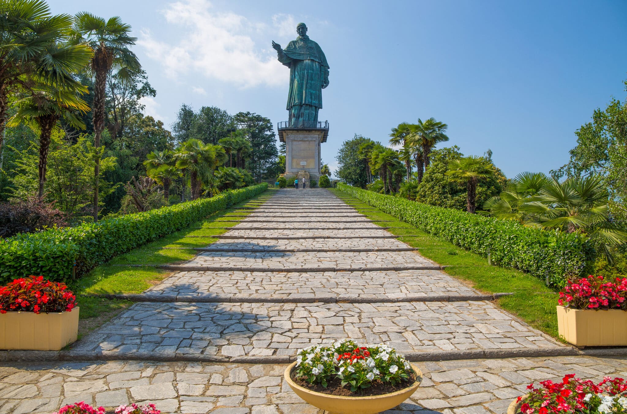 Statua storica su fondo cielato e giardino.