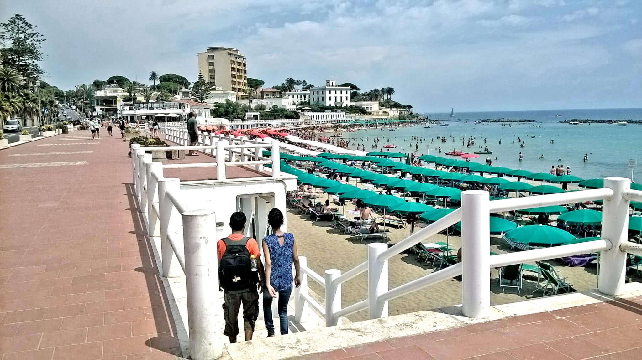 拥挤的海滩上有遮阳伞和长廊。