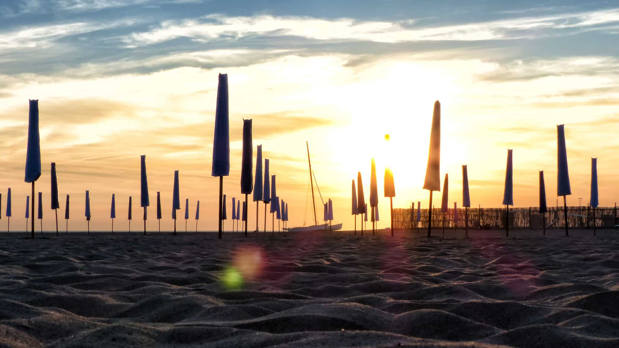 夕阳西下，海滩上的遮阳伞紧闭。